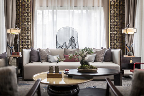 Elegant living room with a large sofa, round table, and decorative lamps.