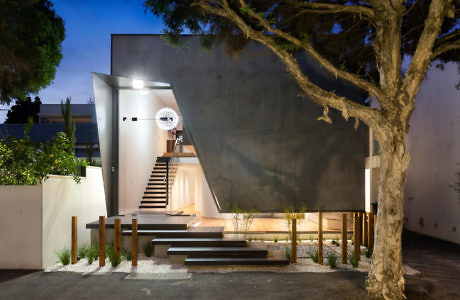 Sleek building entrance with illuminated steps and a large tree at dusk.