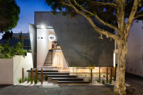 Sleek building entrance with illuminated steps and a large tree at dusk.