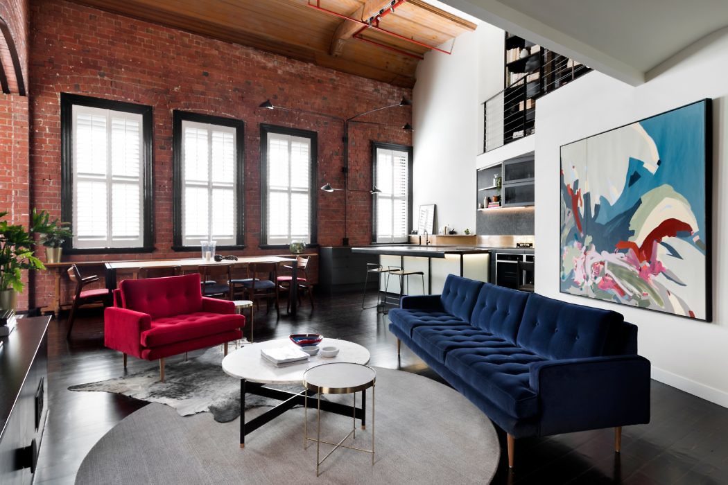 Chic loft living space with exposed brick and vibrant sofas.