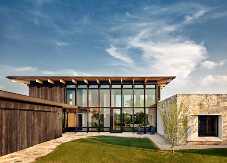 Contemporary house with large glass windows and mixed-material façade.