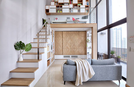 Sleek interior with floating stairs, bookshelf, and comfy couch.