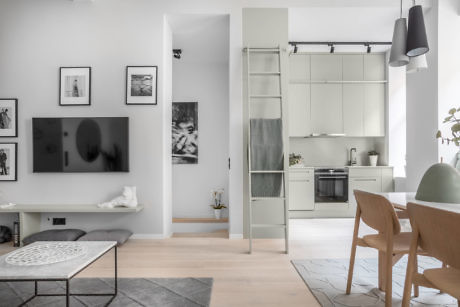 Contemporary living room with sleek kitchen in background.