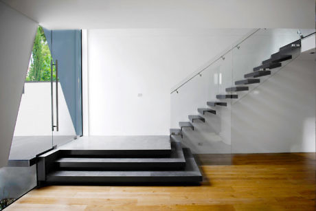 Minimalist interior with floating staircase and contrasting wood floors.