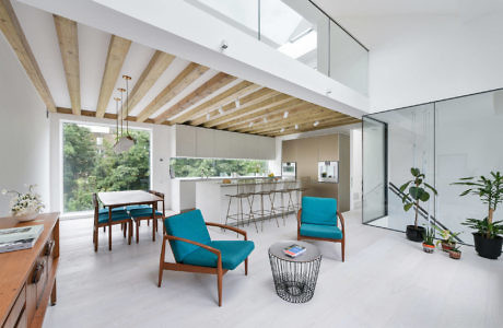 Modern living room with blue chairs, wooden beams, and glass partition.