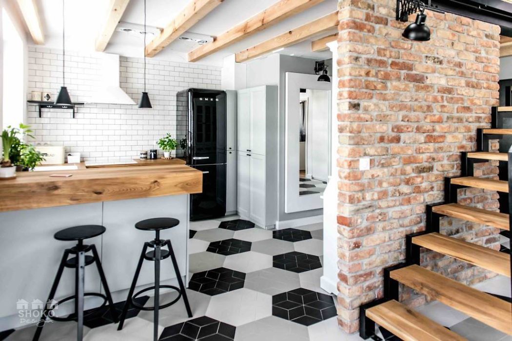 Modern kitchen with brick wall, wooden countertops, and geometric floor tiles.