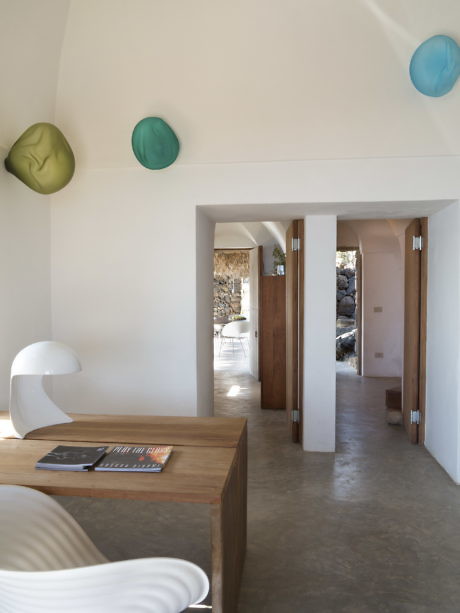 Modern room with white walls, colorful ceiling lights, wooden table, and doorways