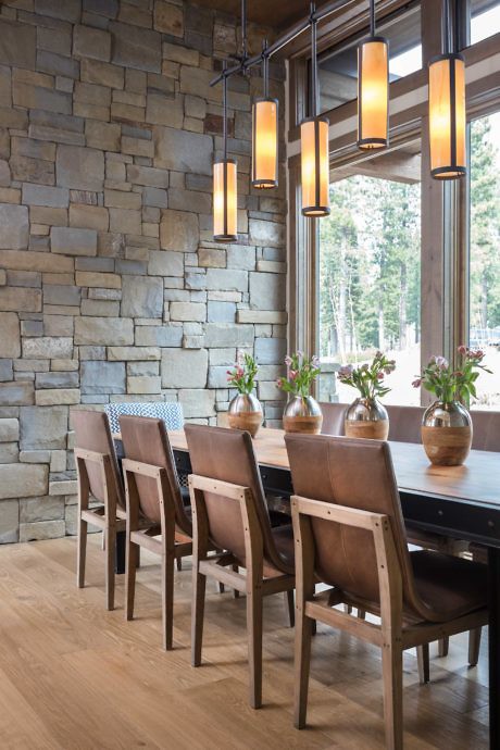 Modern dining room with stone wall, pendant lights, and a wooden table with chairs