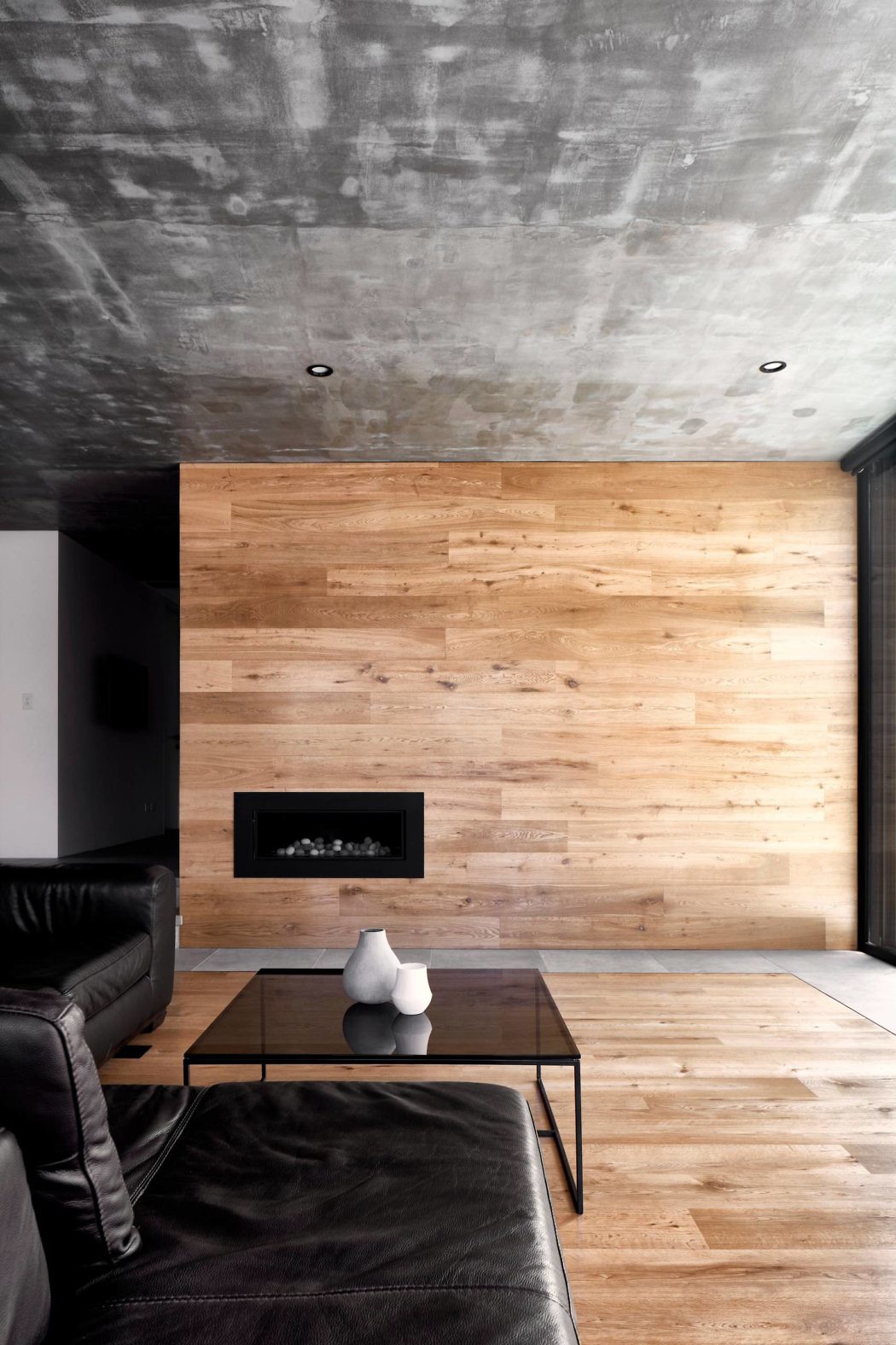 Contemporary room with wood-panel accent wall and concrete ceiling.
