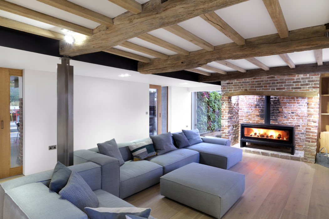 Modern living room with exposed wooden beams, brick fireplace, and large sectional sofa.