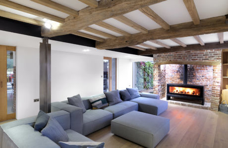 Modern living room with exposed wooden beams, brick fireplace, and large sectional sofa.