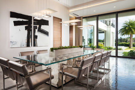 Elegant dining room with glass table, leather chairs, and waterfront view.