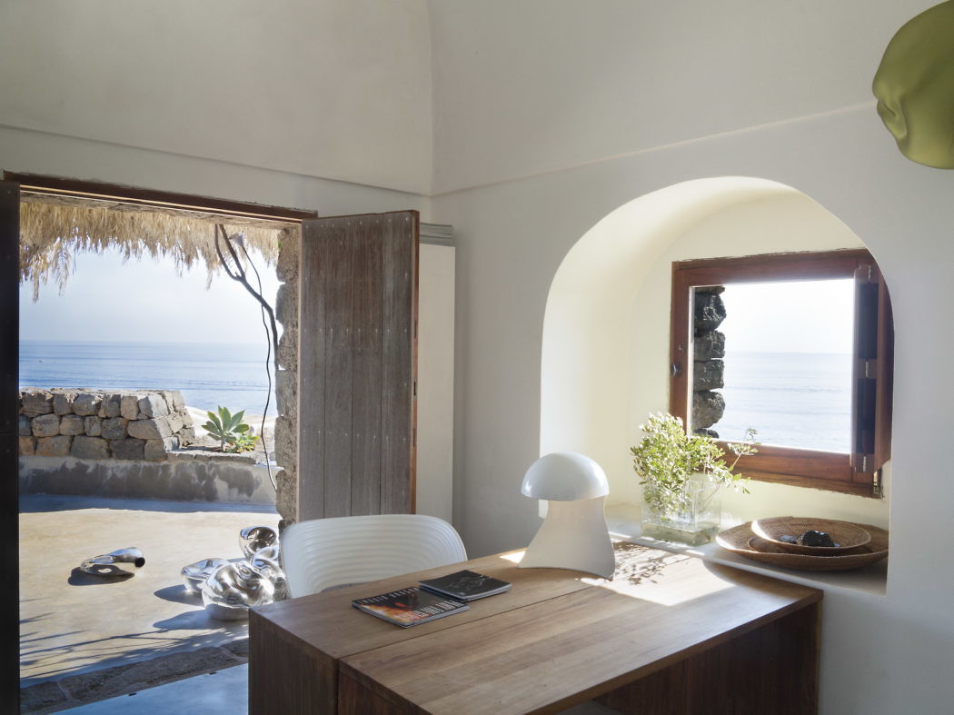 Minimalist seaside room with arched doorway and ocean view.