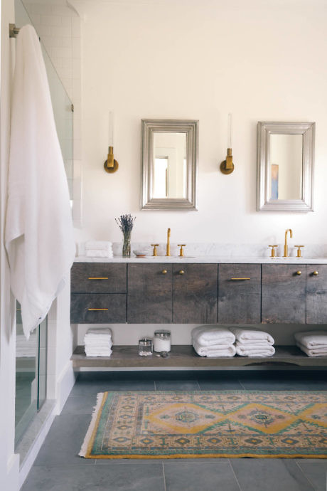 Contemporary bathroom with sleek grey vanity, brass fixtures, and colorful rug.