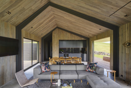 Modern living room with wooden walls, vaulted ceiling, and stylish furniture.