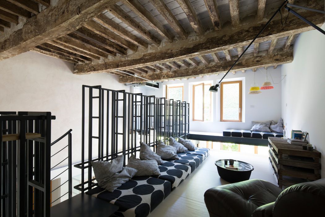 Chic loft with exposed wooden beams, minimalist furniture, and sleek black railing.