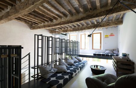 Chic loft with exposed wooden beams, minimalist furniture, and sleek black railing.