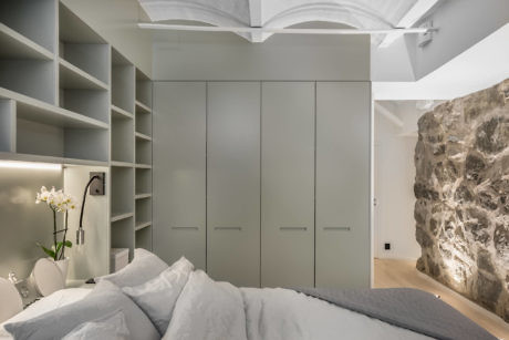 Modern bedroom with built-in cabinets and a natural rock wall feature.