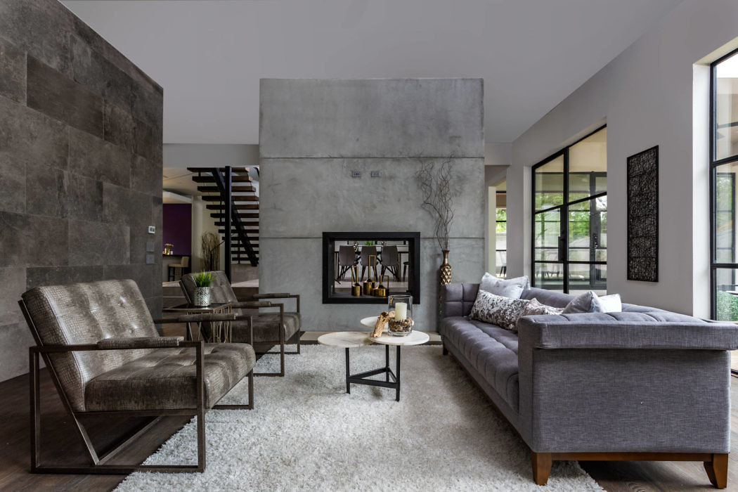 Modern living room with concrete walls, plush sofa, and fireplace.