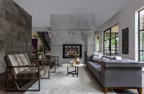 Modern living room with concrete walls, plush sofa, and fireplace.