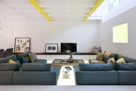 Contemporary living room with teal sofas and yellow accents.
