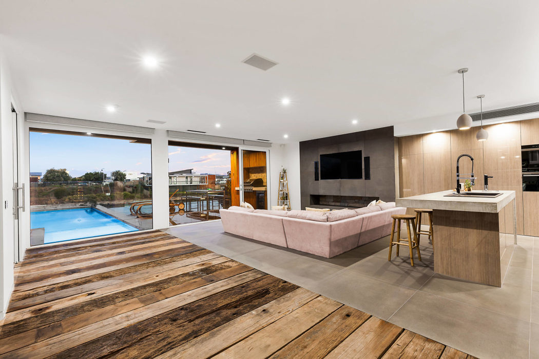 Modern open-plan living area with kitchen and pool view.