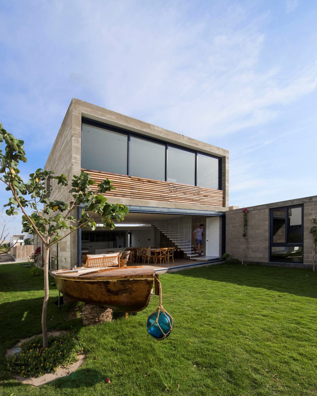 Contemporary concrete house with large windows and a wooden slat balcony.