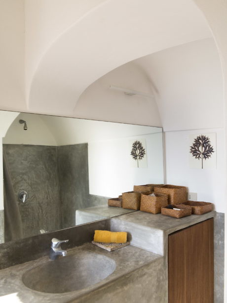 Contemporary bathroom with arched ceiling, concrete sink, and wicker accents.