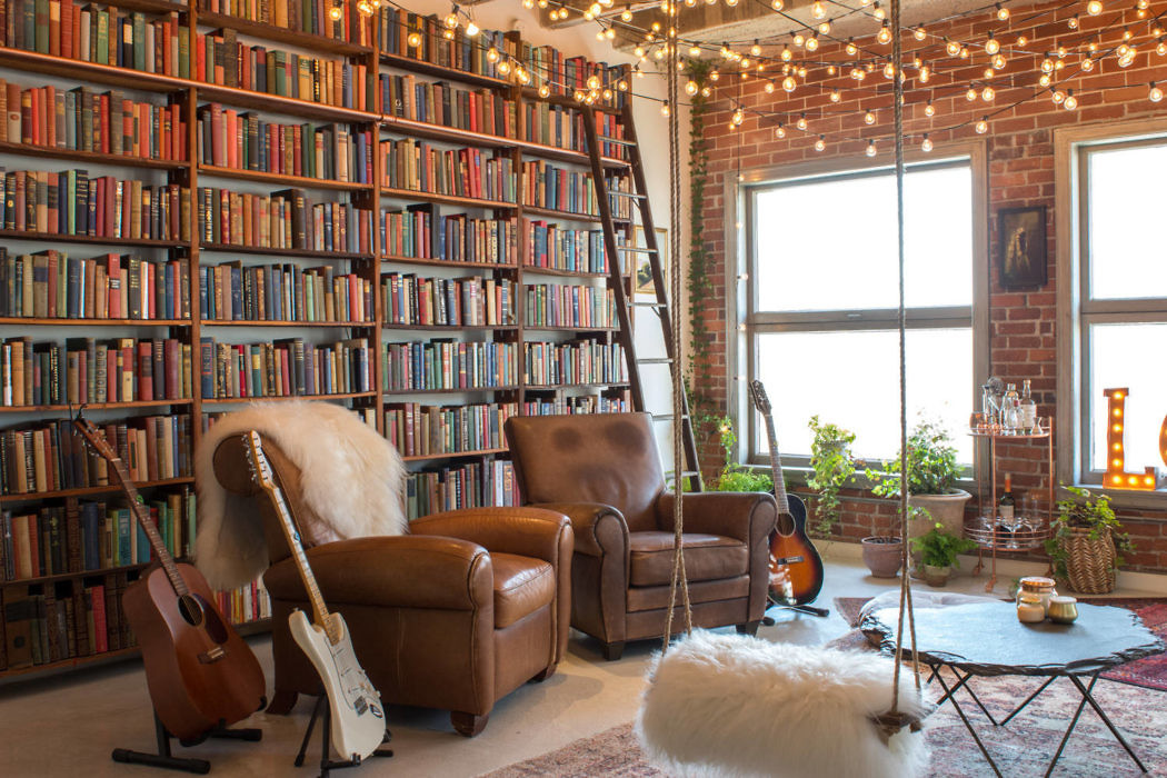Cozy living room with bookshelves, leather chairs, and exposed brick wall