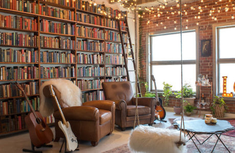 Cozy living room with bookshelves, leather chairs, and exposed brick wall