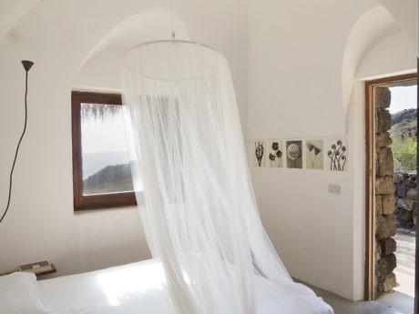 Minimalist white bedroom with archways and a canopy bed.