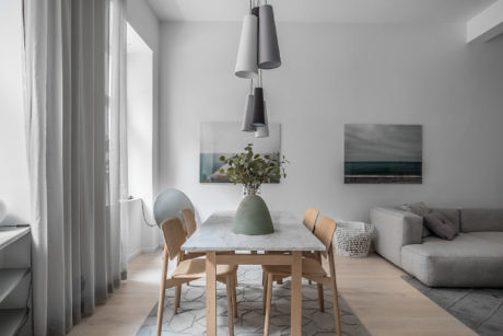 Modern dining room with a wooden table, chairs, pendant lights, and artwork.