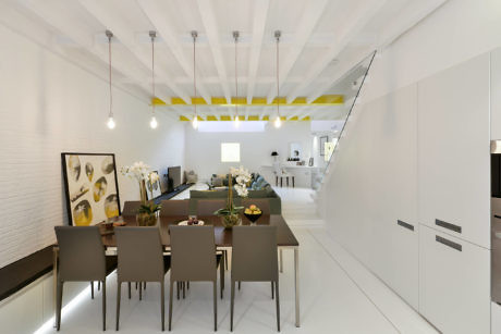 Modern dining room with white decor and yellow ceiling accents.