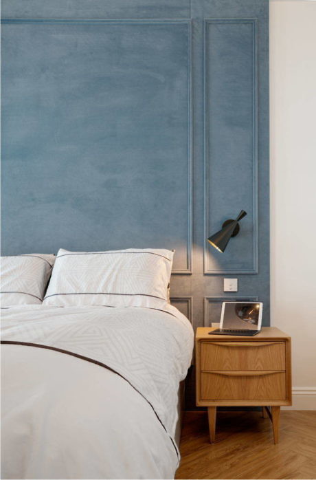 Contemporary bedroom with blue upholstered headboard and wooden nightstand.