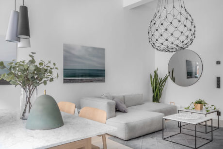 Modern living room in neutral tones with a sofa, table, plants, and pendant