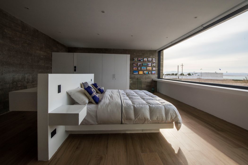 Minimalist bedroom with large window overlooking the sea.
