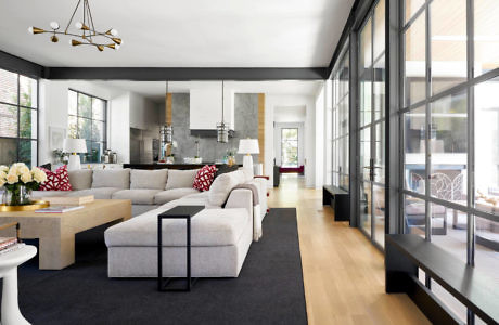 Modern living room with sectional sofa, large windows, and a chandelier.