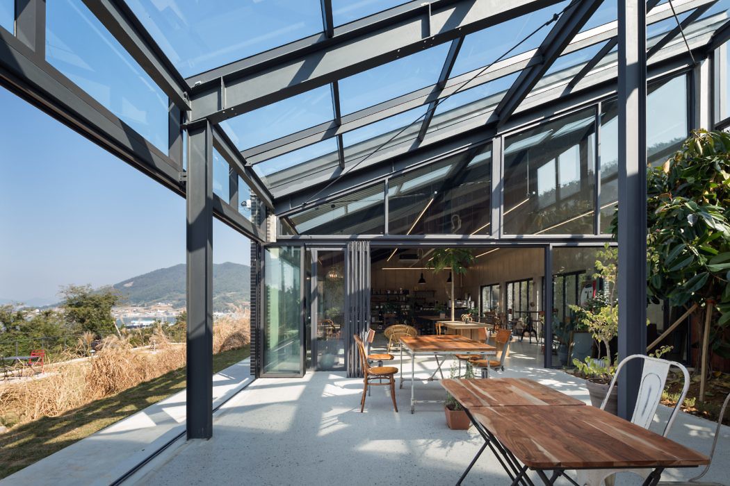Glass-walled dining area with steel frame and panoramic view.