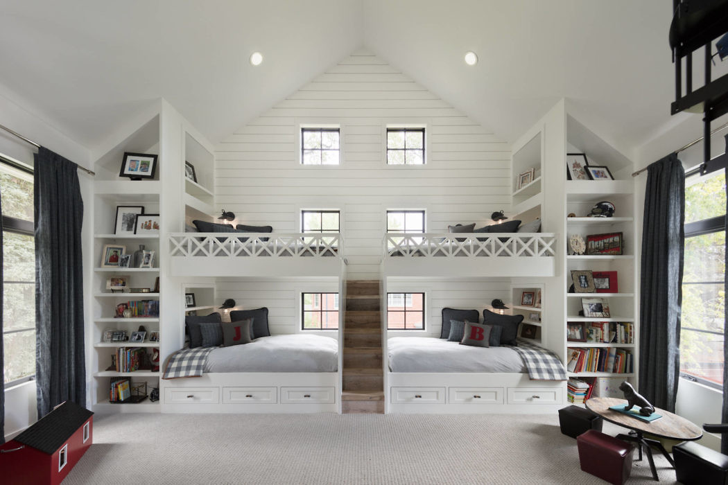 Symmetrical white bedroom interior with two loft beds, bookshelves, and large