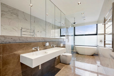 Modern bathroom with dual sinks, large mirror, and freestanding tub.