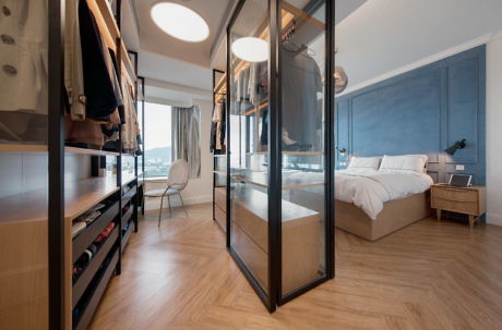 Modern bedroom with glass wardrobe doors and blue accent wall.