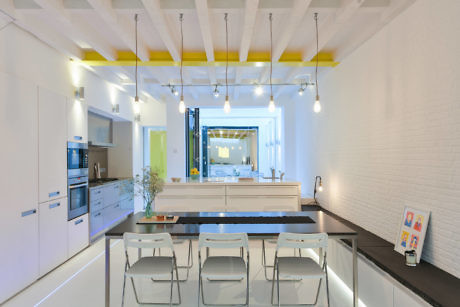 Contemporary white kitchen with central island and exposed beams.