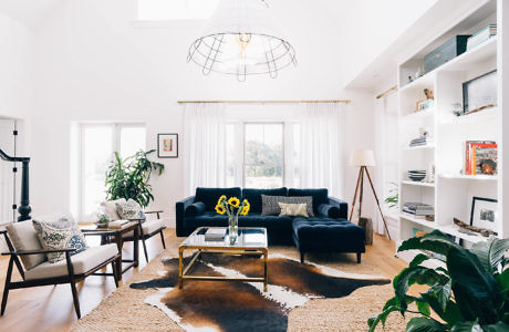 Bright living room with white walls, blue sofas, and cowhide rug.