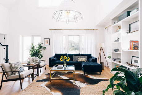 Bright living room with white walls, blue sofas, and cowhide rug.