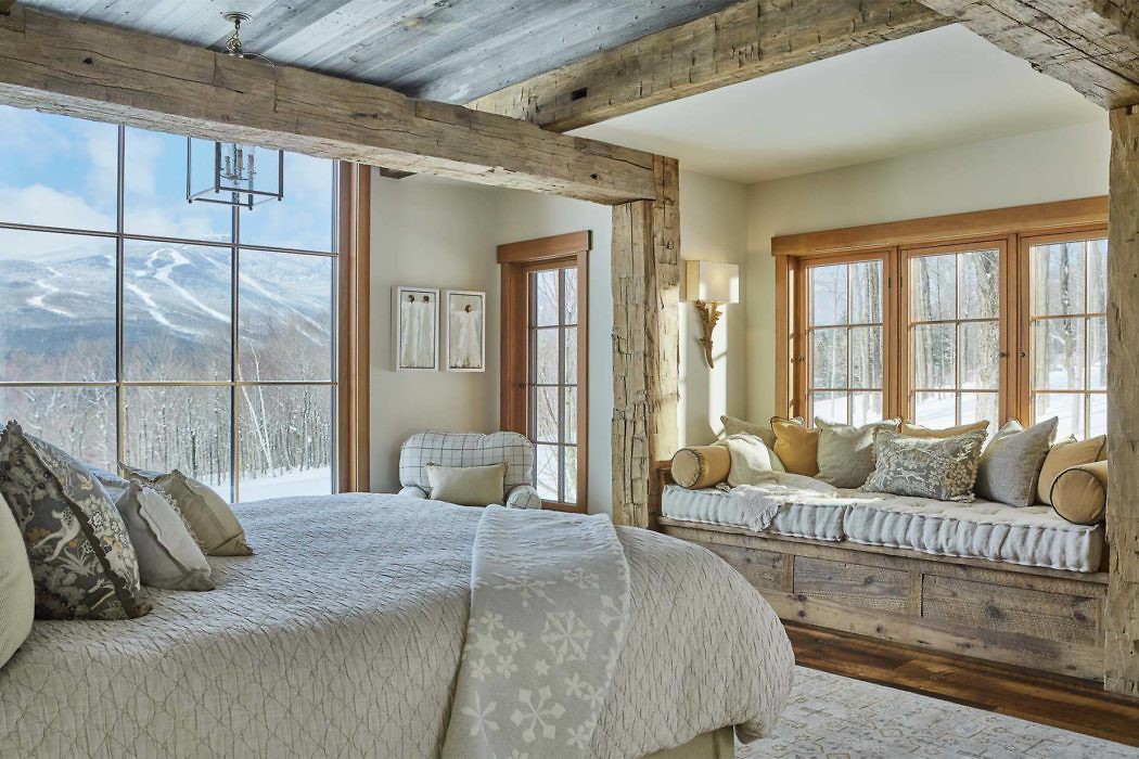 Rustic bedroom with exposed beams and mountain view.