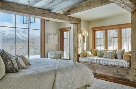 Rustic bedroom with exposed beams and mountain view.