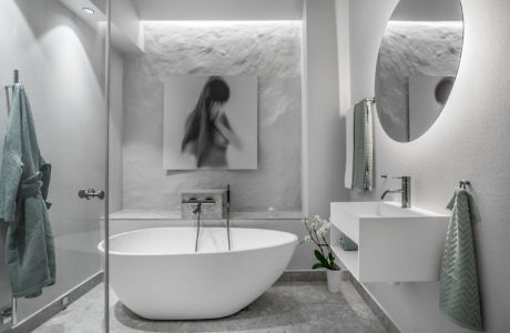 Contemporary white bathroom with oval bathtub and circular mirror.