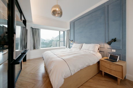 Contemporary bedroom with blue paneling, large windows, and wooden floors.