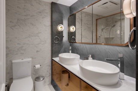 Modern bathroom with double vessel sinks, large mirror, and toilet.