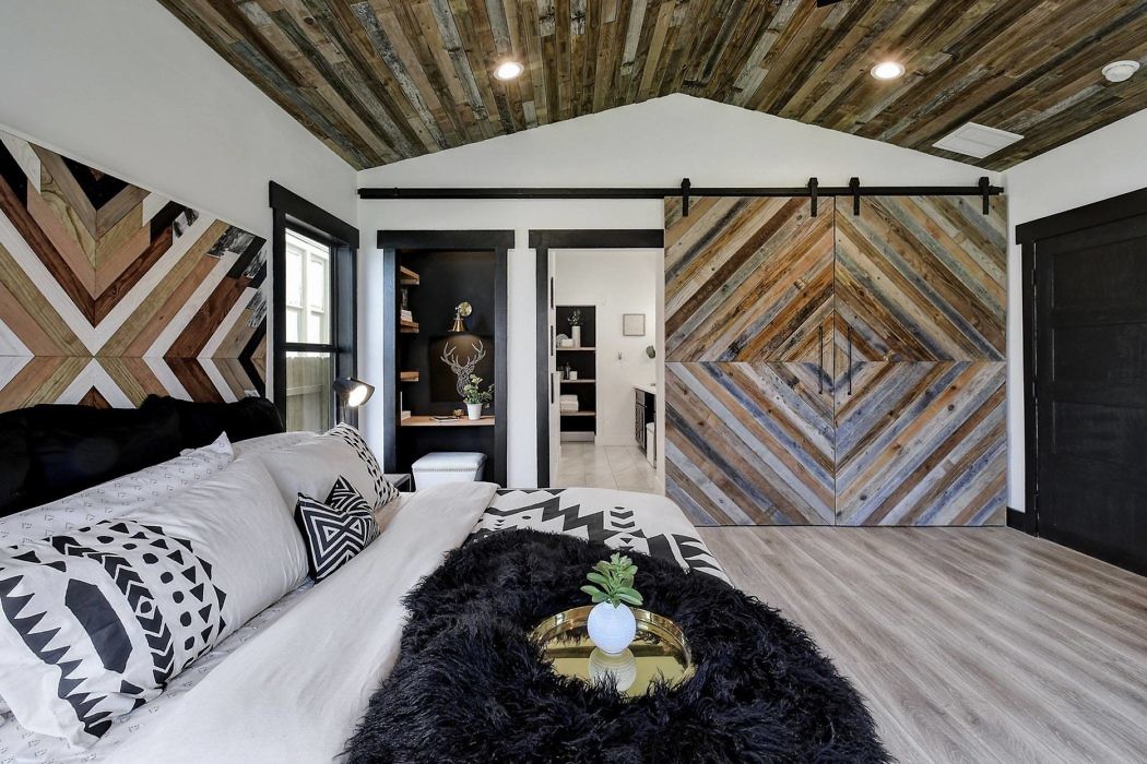 Modern bedroom with patterned wood accent wall and sliding barn door.